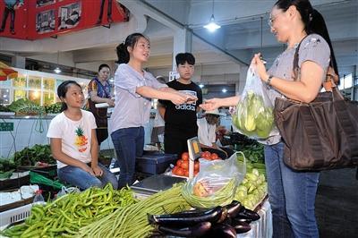 每天上午，孩子们在农贸市场摆摊卖菜。