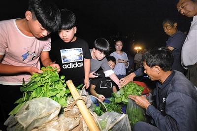 ▲凌晨3点半，孩子们到北山市场批发蔬菜，大家忙着讨价还价。