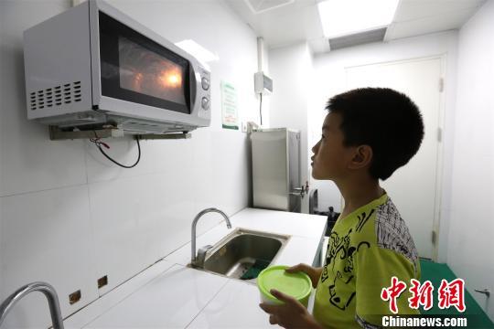 莫钧贤用微波炉热饭给爸爸莫川吃 杨东 摄