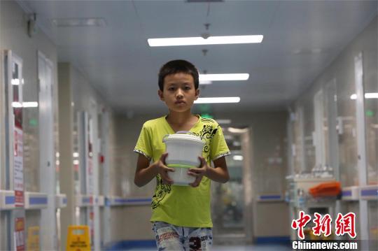 莫钧贤把热好的饭菜送往爸爸病房 杨东 摄