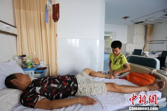 莫钧贤用小石子帮爸爸按摩脚底 杨东 摄