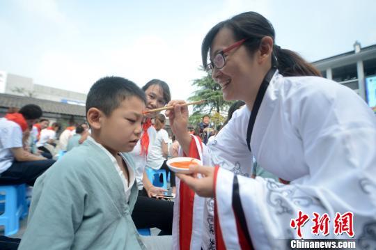 图为师长教师为孩子执笔朱砂启智,并奉上好梦祝贺。 孟德龙 摄