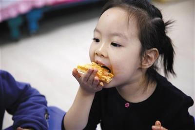2017年10月18日，一名北京安乐幼儿园的孩子在吃食堂大厨专门为幼儿制作的Pizza。资料图片