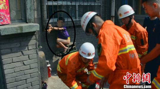 孩子在钢筋防盗网内玩耍时不慎踩空，身体下坠，双腋部位被卡。　视频截图　摄