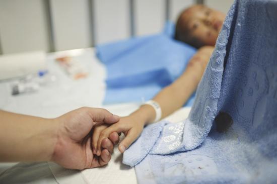 7月11日，湖南省儿童医院，被狗咬伤的小唐（化名）躺在病床上，她的爸爸一边握着女儿的手，一边安慰她。图/记者辜鹏博