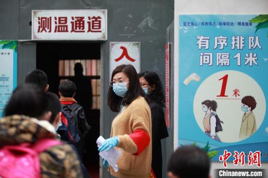 学生相互间隔1米，排队有序通过测温通道进入学校。　孟德龙 摄