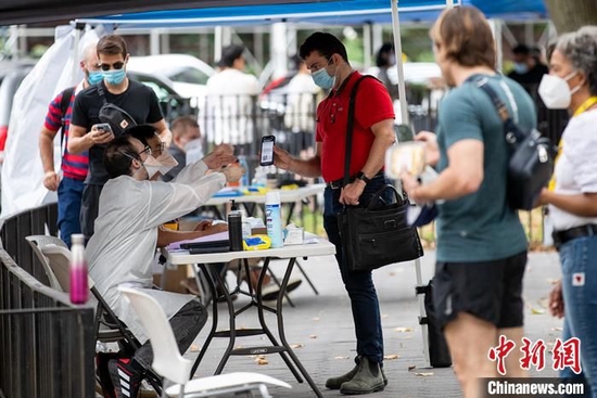 当地时间7月26日,美国纽约曼哈顿一处猴痘疫苗接种点,工作人员为民众验证预约信息。 中新社记者 廖攀 摄