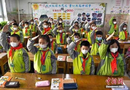 3月23日，新疆维吾尔自治区乌鲁木齐市42小学的学生们在教室内举行升国旗仪式。中新社记者 刘新 摄