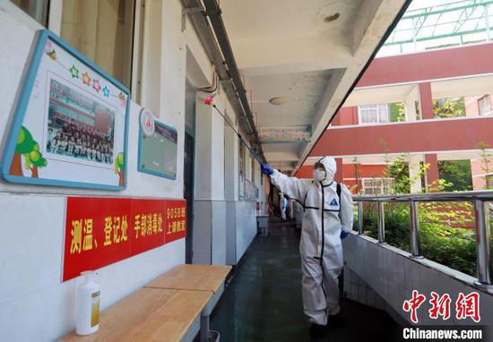 图为消防员正在对上课教室外的走廊区域进行全面消杀。 王方 摄