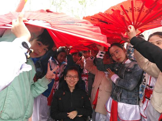 学校运动会开幕式当天忽然下起了小雨，同学们用手中表演用的扇子自发为宣诺挡雨。受访者供图