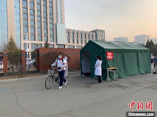 图为学生经过体温检测后进入校园。 张林虎 摄