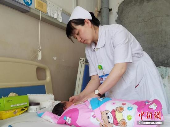 资料图:怀孕9个月的吕梁市人民医院儿科护士刘丽,在病房照顾患儿。闫彩琴 摄