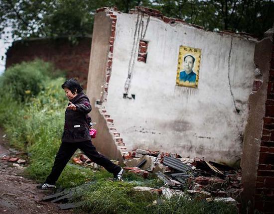 2014年4月25日，湖南省衡东大浦镇，一位居民从一处破旧的房中跨出，由于离化工厂太近，多年前她从此地搬迁离开。 杨一 澎湃资料