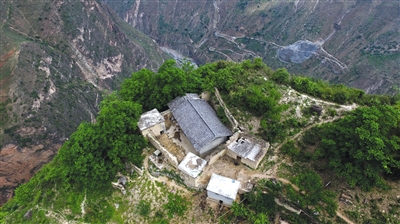 5月13日,无人机俯瞰位于悬崖边缘的村民某色拉则的家,他家的后院门推开就是悬崖,房屋所在位置也是全村最高点。