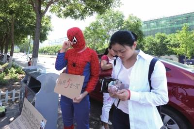 何女士当街扮演“蜘蛛侠”,举牌求路人拍照,为身患噬血细胞综合征的5岁半儿子筹钱治疗。