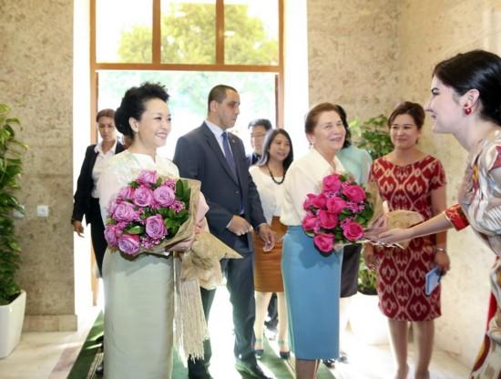 彭丽媛受到学院师生热烈欢迎。身着中国旗袍和乌民族服装的学生向来宾敬献鲜花。新华社记者丁林摄