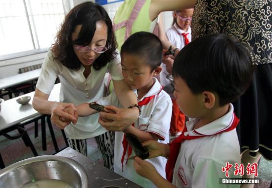 资料图：多名校园妈妈与留守孩子们一起包粽子，迎接即将到来的端午节。中新社发 杨甜艺 摄