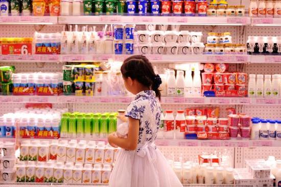 2016年8月9日，山东青岛一商场，一位小朋友在选购奶制品饮料。 视觉中国 图
