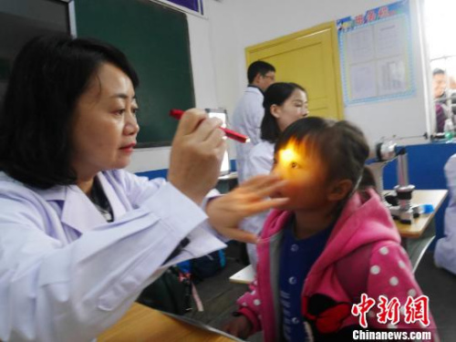 资料图:眼科专家在为山区孩子检查视力。 潘佳 摄