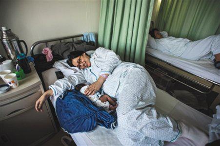 2016年3月18日,朝阳区妇幼保健院产科病房里,一位母亲看着刚出生的孩子。图/视觉中国