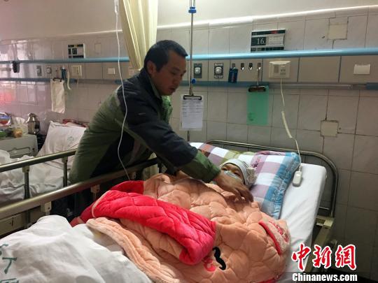 图为杨群树在医院照顾杨泽辉。　朱柳融　摄