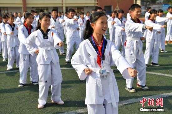 资料图：3月13日，海口城西中学操场，千名学生身着统一的跆拳道服进行“跆拳礼仪广播体操+跑操”大课间体育运动。中新社记者 骆云飞 摄