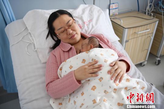 母亲将孩子拥袈溱胸前,与婴儿近距离接近。 武俊杰 摄