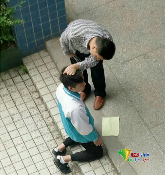 张姓先外行拿带插线板的电线,另一只手揪住跪在地上的学生的头发。