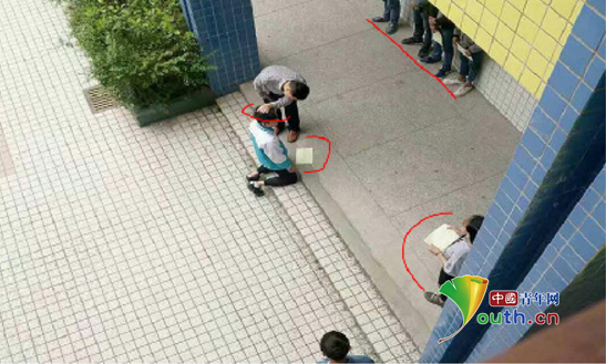 图片显示,张姓师长教师揪住跪在地上的学生的头发,学生面前还有一排学生靠墙站着,侧面也有学生站着。