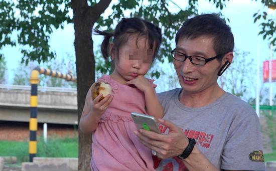 司机师傅胡爱松陪依依玩,给她放手机里的动画片。 彭湃消息记者 朱莹 图