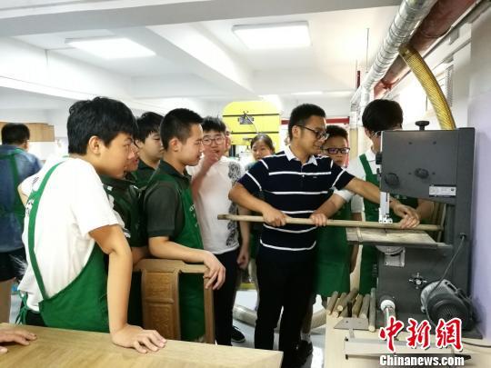 负责指导的王坚老师正在教导学生用机器加工木材。　钟升　摄