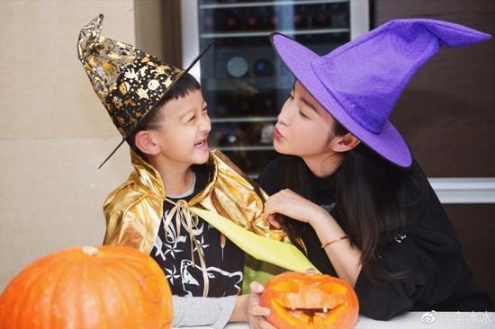 小萌娃打扮成小王子一身金色礼帽和披肩，李冰冰则头戴紫色尖帽，两个人一起做南瓜灯。