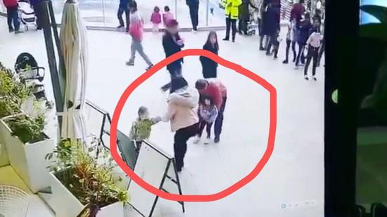 监控视频截图，红衣男子突然将殷女士的孩子抱起欲离开。