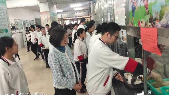 陈经纶中学高中校区校长牟成梅在食堂与学生一同排队取餐。 校方供图