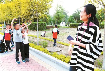 班上的一名学生要竞聘大队委员，在操场上练演讲，看到学生的表现， 任威老师露出笑容