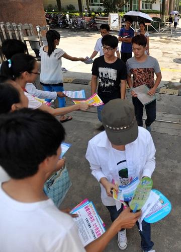 市一所中学门口,几名校外培训机构宣传人员在发放暑假培训招生宣传单