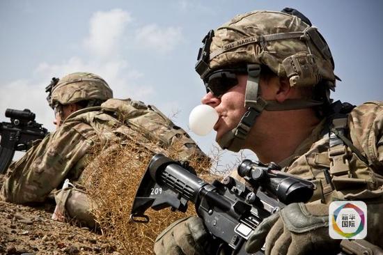 资料：2013年2月3日，一名在阿富汗坎大哈附近执行任务的美国陆军士兵吹口香糖泡泡。（新华／路透）