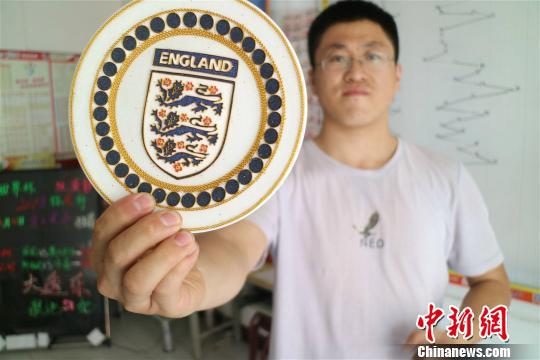 足球爱好者吕一民展示英格兰国家队队徽。 额丽其格