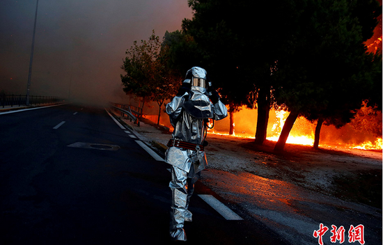 2018年7月23日，希腊雅典附近发生山火，一名消防队员穿行火场。COSTAS BALTAS