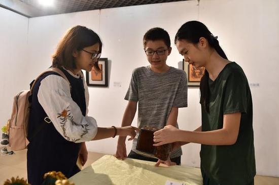 本次展览最年轻的皮雕达人,初二学生叶度羽(右)正在向观众介绍自己的作品