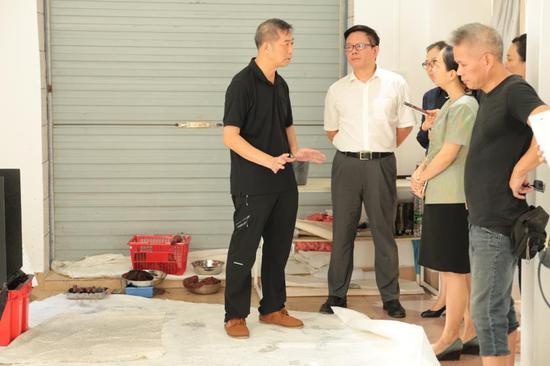 “参观艺术家工作室”环节中，香港艺术家叶志明先生（左）与深圳市盐田区政府副区长周敏先生（左二）、其他领导、媒体记者等积极交流中
