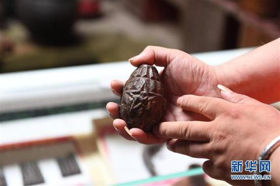 6月12日，罗小龙在展示一枚印有苏区标志的手雷。新华社记者 周密 摄
