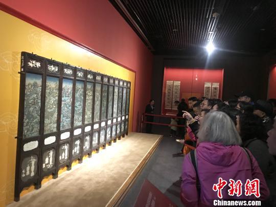 图为观众在围观紫檀木边架漆地嵌象牙广西府州围屏。 钟建珊 摄