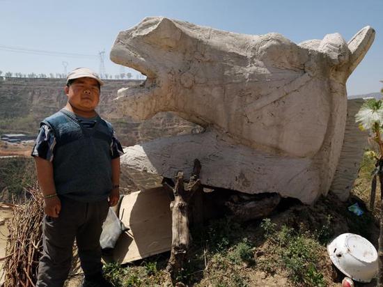 靳红强和他最喜欢的马头雕塑。新京报记者 王巍 摄