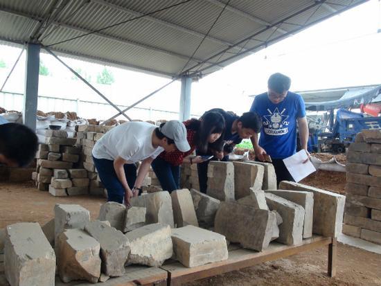 图7 中国人民大学研究生在曹魏大墓工地现场考察出土墓砖（李重蓉摄影）