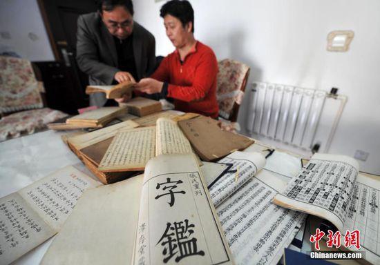 赵无双（右）在家中展示他珍藏的各种古籍。