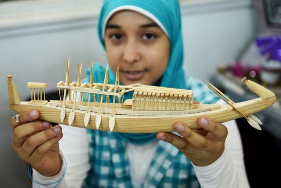 8月30日，在埃及开罗古埃及艺术品复刻中心，一名女孩展示法老船复制品。