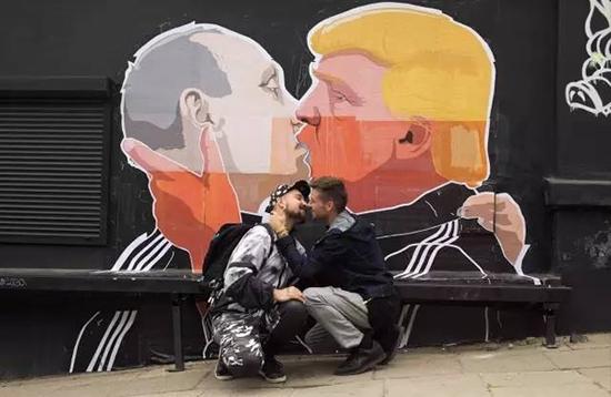同性恋人士在川普与普京的涂鸦前留影。