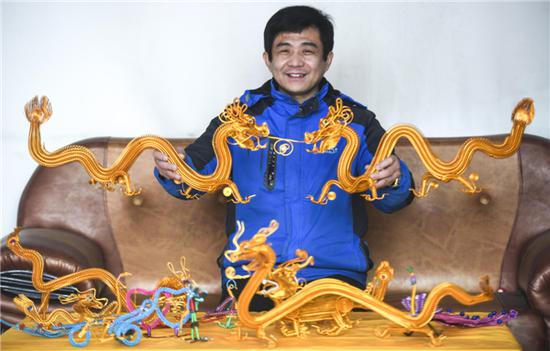       12月24日，王强在展示“双龙戏珠”等弹簧工艺品。