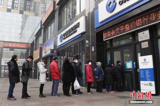 点击图片翻到下一页>> 北京市民排队兑换鸡年贺岁纪念币。 中新社记者 李慧思 摄